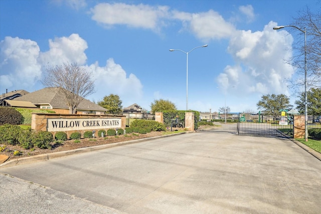 view of road featuring a gated entry, curbs, street lighting, and a gate