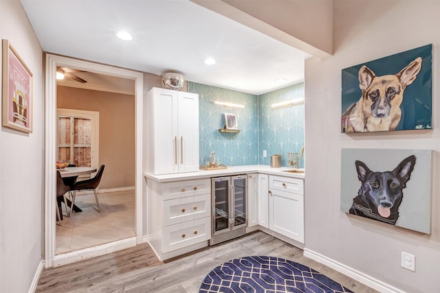 bar with wine cooler, light wood-style flooring, wet bar, and a sink