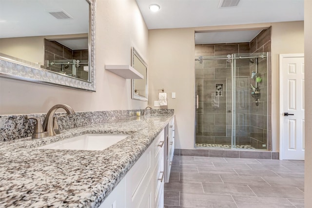 full bathroom featuring double vanity, visible vents, a stall shower, and a sink