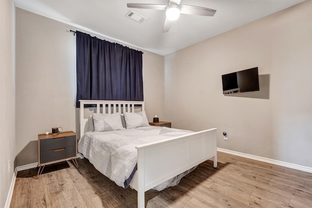 bedroom with ceiling fan, visible vents, baseboards, and wood finished floors