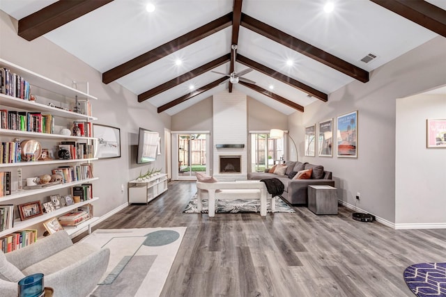 living area featuring visible vents, beam ceiling, a fireplace, wood finished floors, and high vaulted ceiling