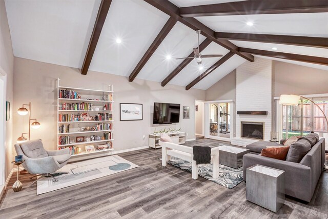 living room with beamed ceiling, a fireplace, wood finished floors, high vaulted ceiling, and a ceiling fan