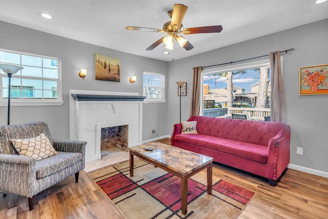 living room featuring a brick fireplace, baseboards, ceiling fan, recessed lighting, and wood finished floors