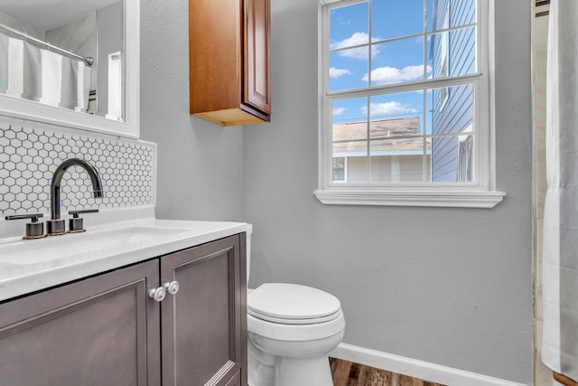 full bath with baseboards, toilet, a shower with shower curtain, wood finished floors, and vanity