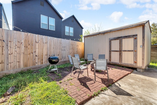 view of patio / terrace featuring a storage unit, a fenced backyard, a grill, and an outdoor structure