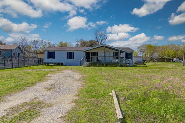 manufactured / mobile home featuring driveway, a front lawn, and fence