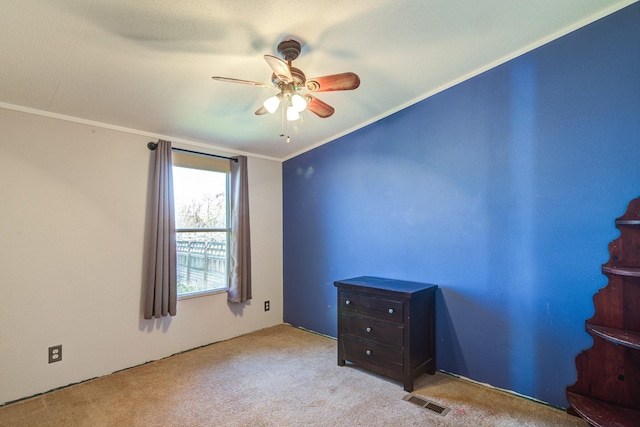 unfurnished bedroom featuring carpet flooring, a ceiling fan, visible vents, and ornamental molding