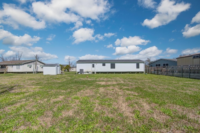 back of property featuring an outbuilding, a storage unit, fence, and a yard