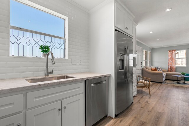 kitchen with tasteful backsplash, open floor plan, ornamental molding, stainless steel appliances, and a sink