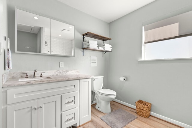 bathroom with baseboards, toilet, wood finished floors, and vanity