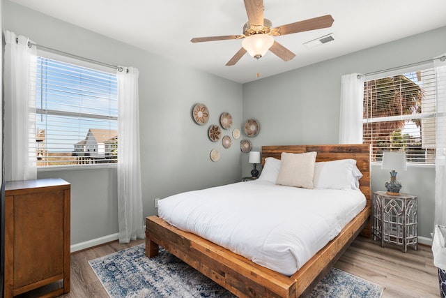 bedroom with light wood-style flooring, baseboards, visible vents, and ceiling fan