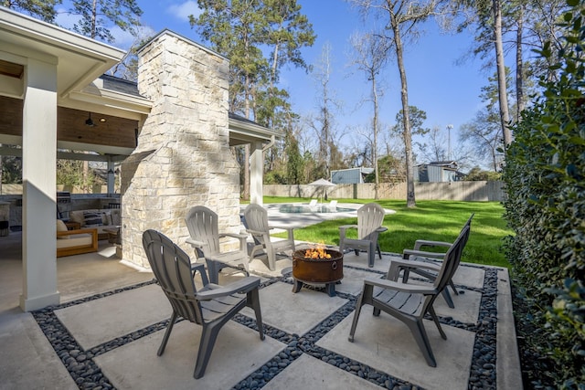 view of patio with an outdoor fire pit, a fireplace, and fence