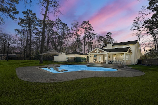 pool featuring an outbuilding, fence, an in ground hot tub, central air condition unit, and a lawn