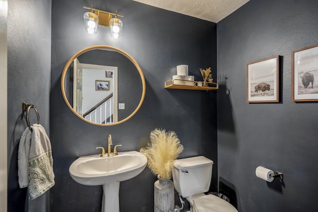 bathroom with toilet, a textured wall, and a sink