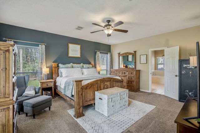 bedroom with visible vents, light colored carpet, ensuite bath, and a ceiling fan