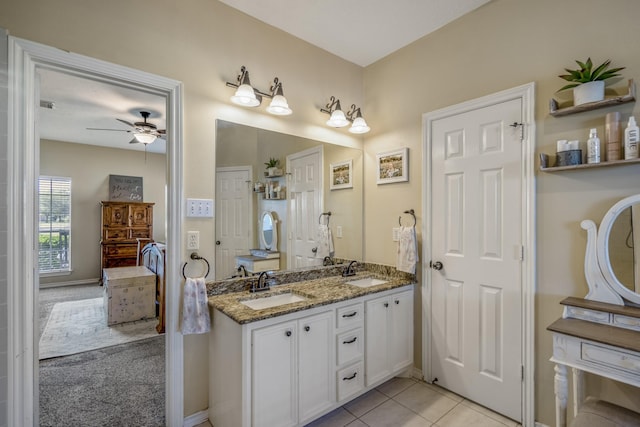 ensuite bathroom with double vanity, a ceiling fan, tile patterned floors, and a sink