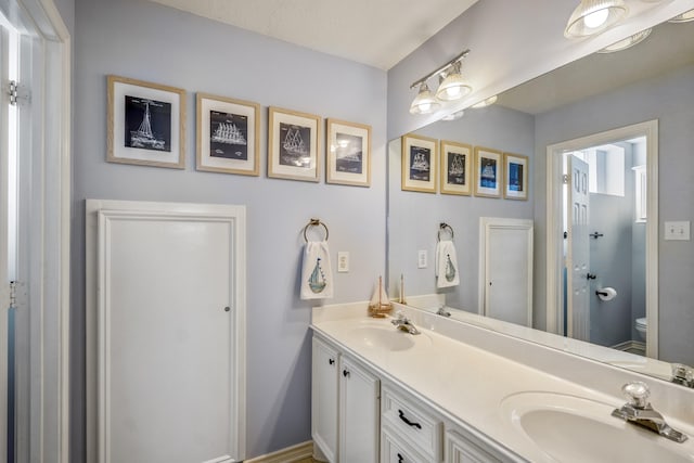 full bath featuring double vanity, toilet, and a sink