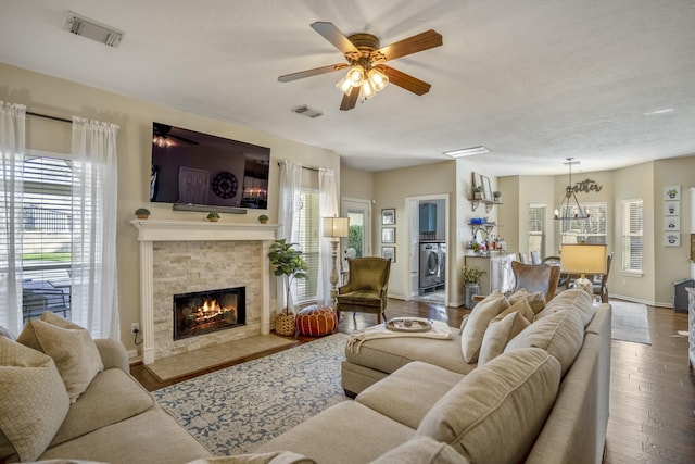 living room featuring visible vents, a fireplace, washer / clothes dryer, and wood finished floors