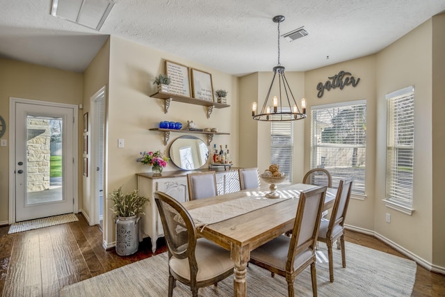 dining room featuring a notable chandelier, wood finished floors, visible vents, and a textured ceiling