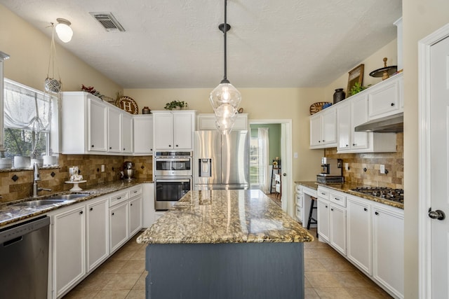 kitchen with visible vents, a sink, under cabinet range hood, appliances with stainless steel finishes, and a center island