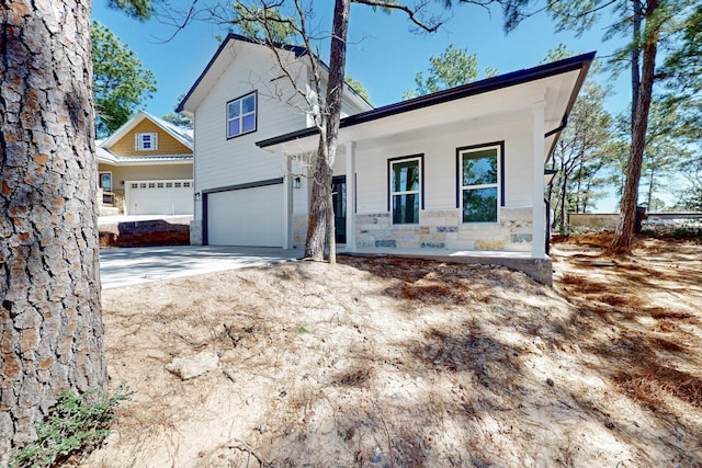 view of front of home with stone siding, a porch, and concrete driveway