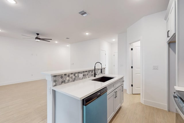 kitchen with dishwashing machine, visible vents, a sink, light countertops, and light wood-style floors