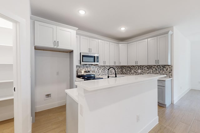 kitchen featuring tasteful backsplash, recessed lighting, stainless steel appliances, light wood-style floors, and light countertops