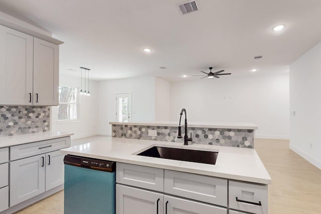 kitchen with visible vents, backsplash, light countertops, dishwashing machine, and a sink