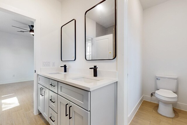 full bathroom featuring toilet, wood finished floors, a ceiling fan, and a sink