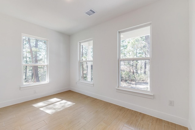 spare room with visible vents, light wood-style flooring, and baseboards