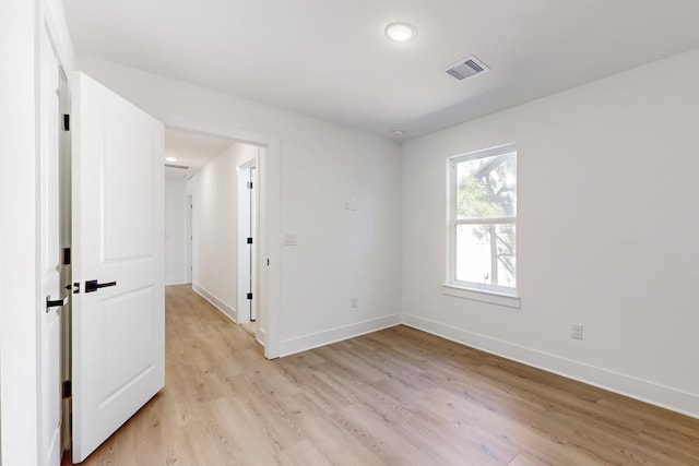 unfurnished room featuring light wood-style flooring, baseboards, and visible vents