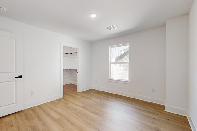 unfurnished room with light wood finished floors, visible vents, and baseboards