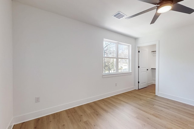 unfurnished bedroom with a ceiling fan, baseboards, visible vents, light wood finished floors, and a spacious closet