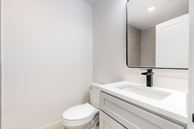 half bath featuring recessed lighting, toilet, and vanity