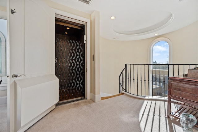 corridor featuring baseboards, carpet, a tray ceiling, an upstairs landing, and recessed lighting