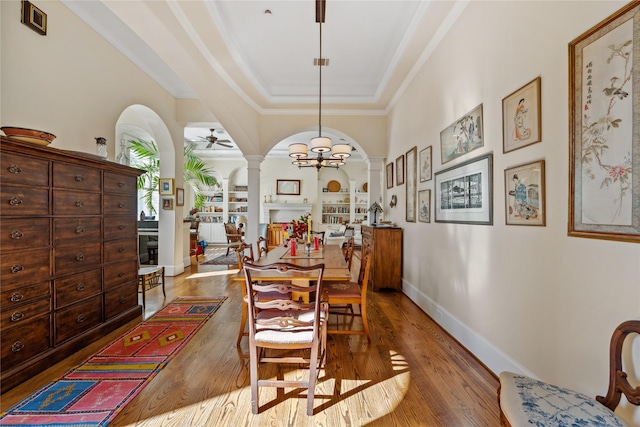 dining room featuring baseboards, decorative columns, arched walkways, a ceiling fan, and wood-type flooring