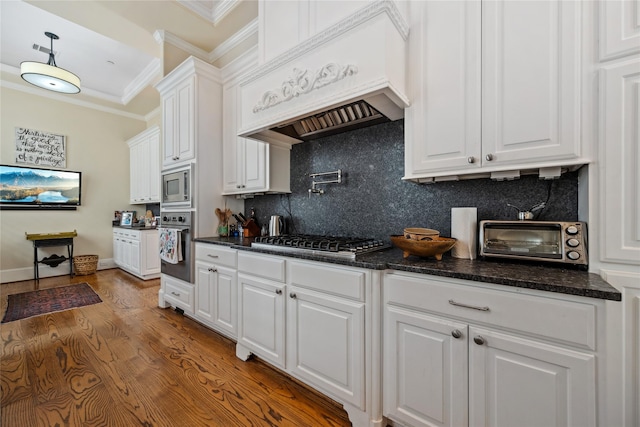 kitchen featuring premium range hood, white cabinetry, stainless steel appliances, crown molding, and a toaster