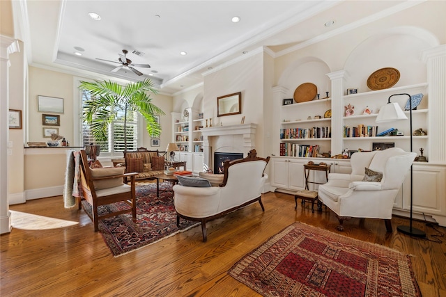 living room with visible vents, built in shelves, a fireplace, and wood finished floors