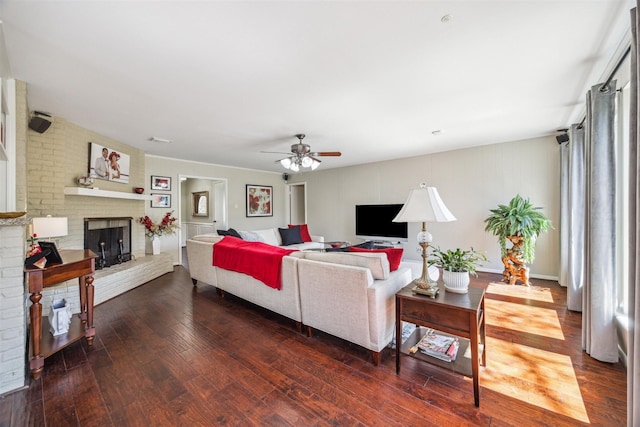 living area featuring a brick fireplace, dark wood finished floors, and a ceiling fan