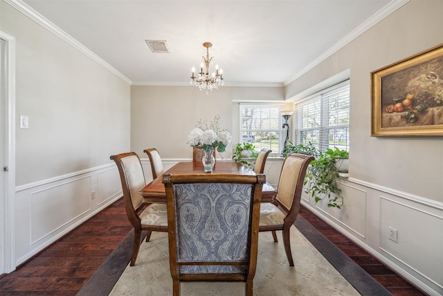 dining room featuring visible vents, a wainscoted wall, ornamental molding, wood finished floors, and a notable chandelier