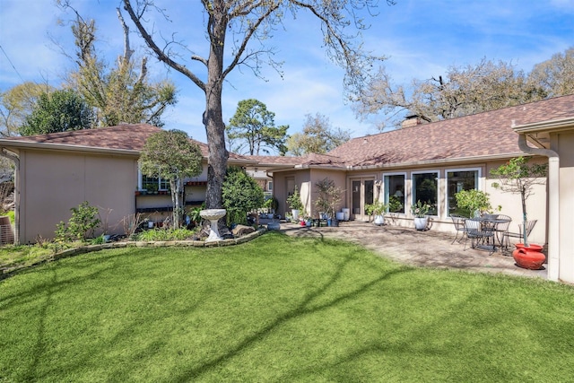 rear view of property featuring a patio, a yard, and stucco siding