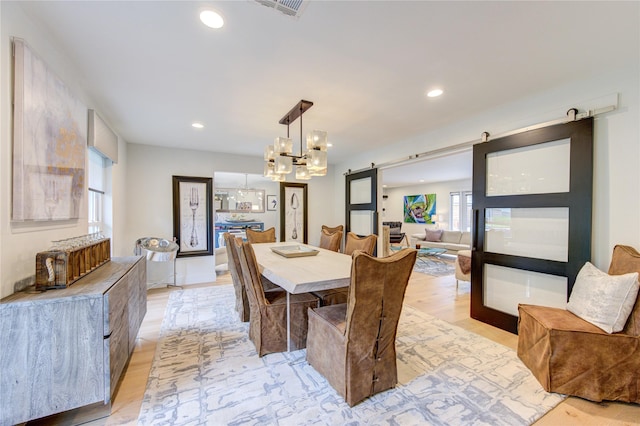 dining room featuring a barn door, recessed lighting, and light wood finished floors