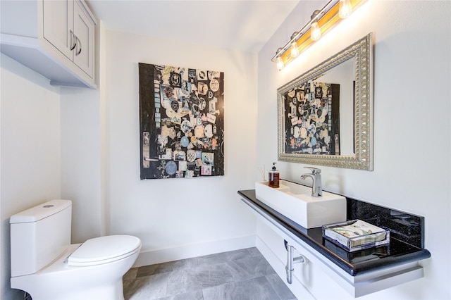 bathroom featuring toilet, vanity, and baseboards