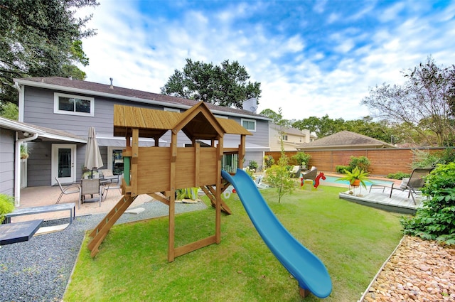 view of playground featuring a patio, a yard, and a fenced backyard