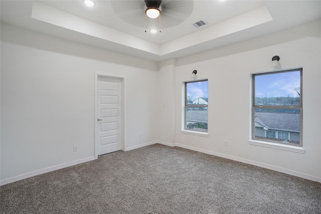 carpeted spare room with visible vents, a raised ceiling, and baseboards