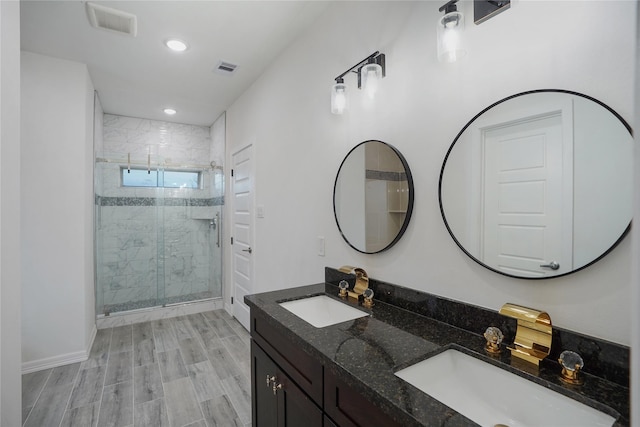 bathroom with a sink, visible vents, a stall shower, and double vanity