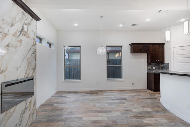 kitchen with dark countertops, decorative backsplash, dark brown cabinets, and light wood-style floors