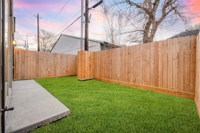 yard at dusk featuring a fenced backyard