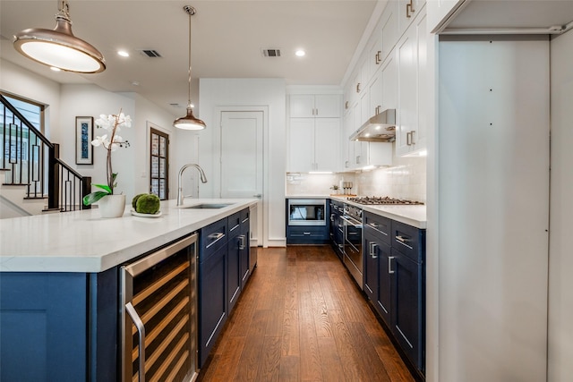 kitchen featuring blue cabinetry, beverage cooler, under cabinet range hood, white cabinets, and a sink