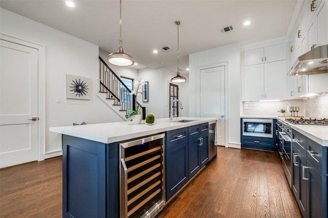 kitchen with blue cabinets, a sink, wine cooler, appliances with stainless steel finishes, and white cabinets